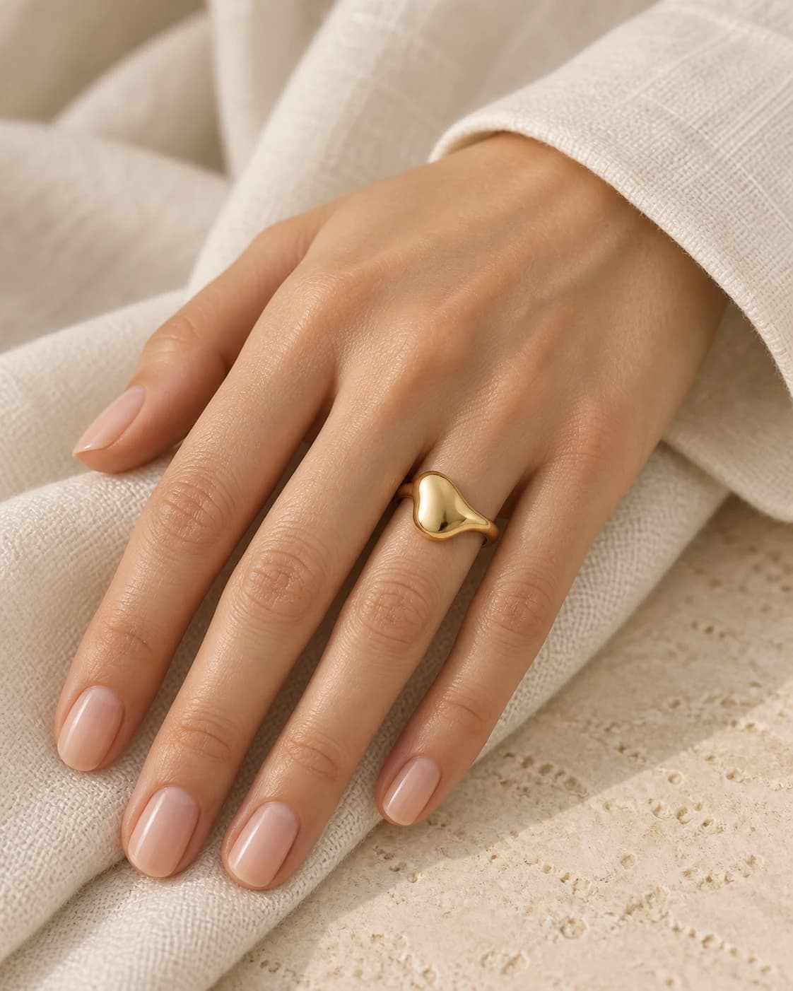 Still-image concept of a sculptural gold-tone ring worn on a hand